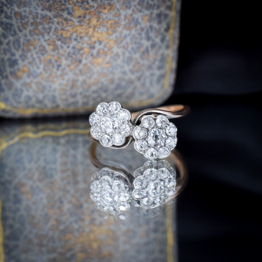 An antique diamond ring featuring two circular daisy clusters on a crossover metal twist band. View IV