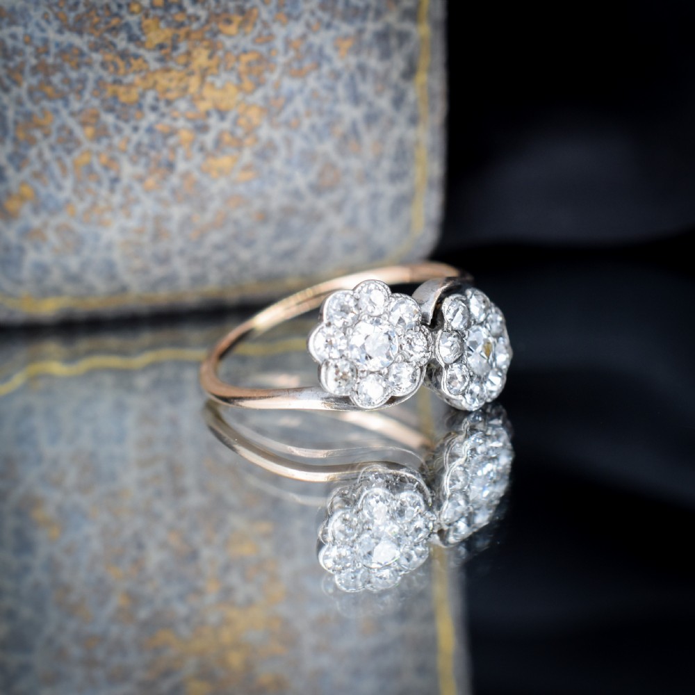 An antique diamond ring featuring two circular daisy clusters on a crossover metal twist band. View VI
