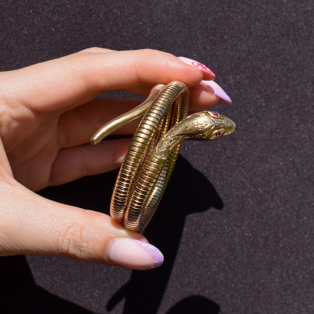 A vintage coiled 9ct yellow gold snake bangle featuring hand-engraved head detailing and red gemstone eyes. View XIII