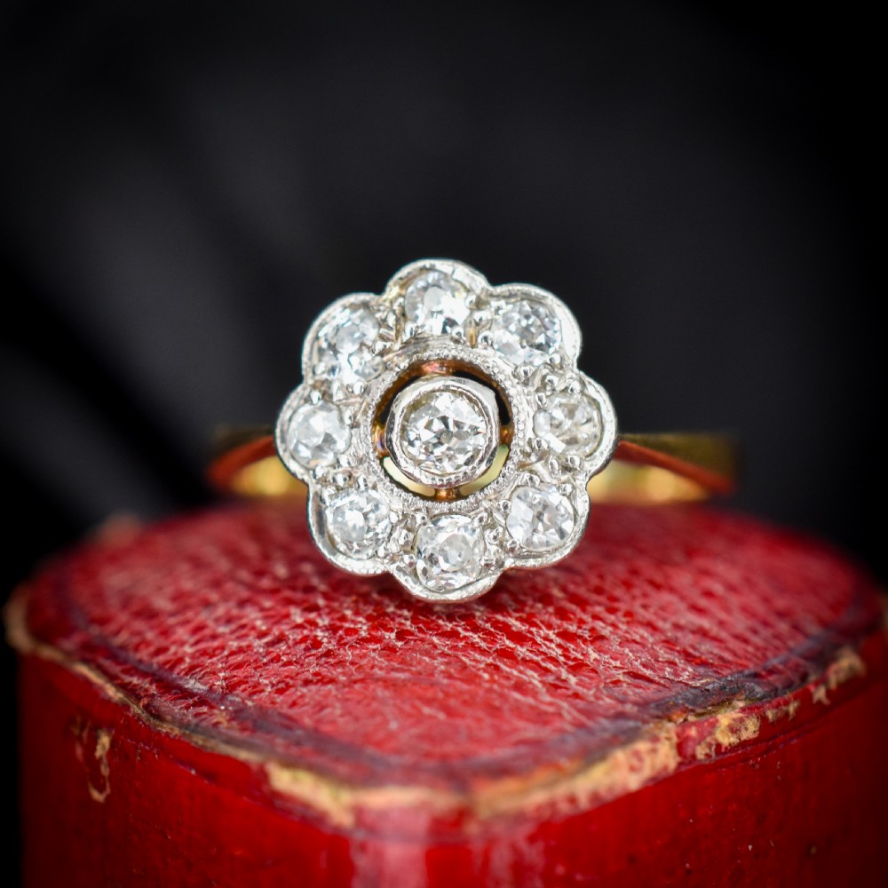 An antique diamond cluster ring in a flower shape set in platinum with an 18ct yellow gold band.