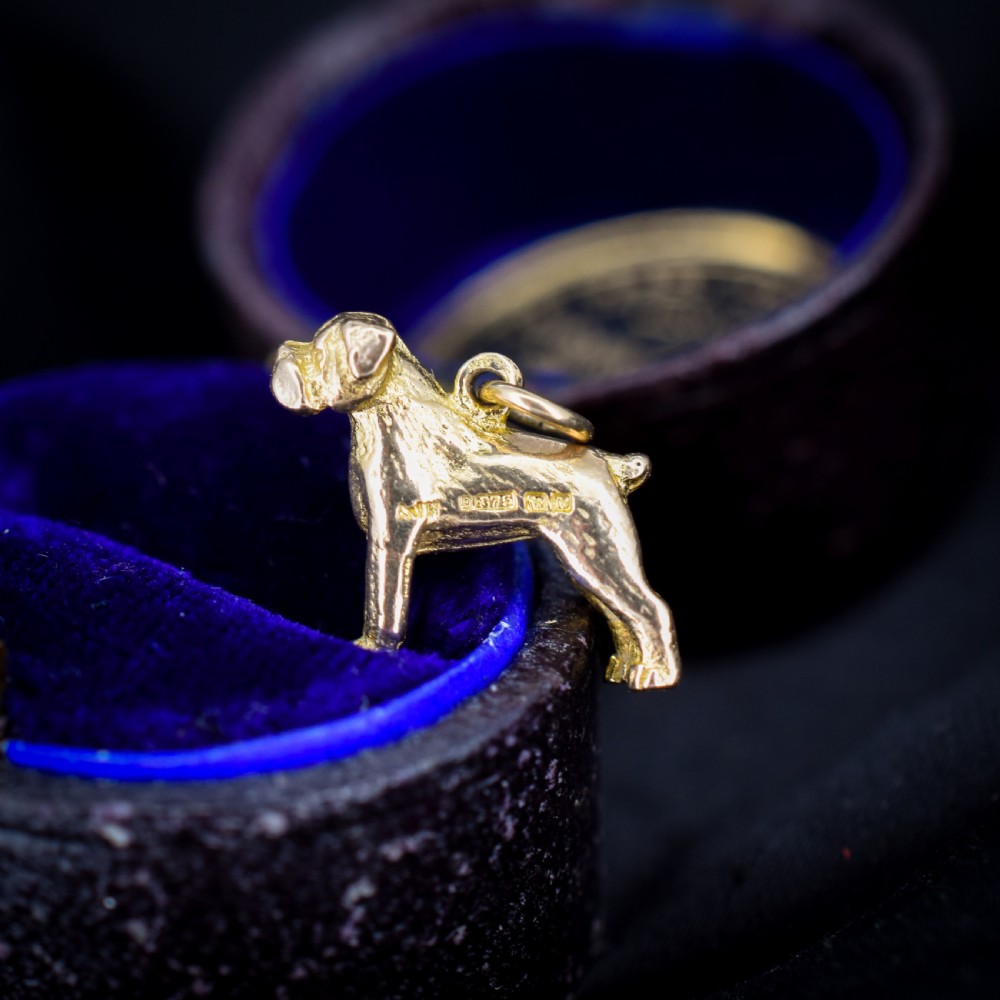 A solid 9ct yellow gold charm shaped as a standing boxer dog with visible hallmarks stamped on its side.