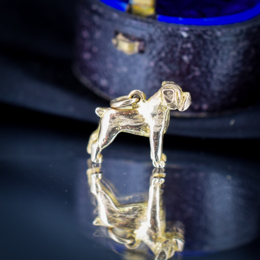 A solid 9ct yellow gold charm shaped as a standing boxer dog with visible hallmarks stamped on its side. View II
