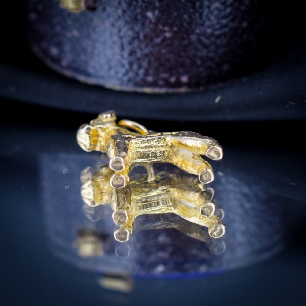 A solid 9ct yellow gold charm shaped as a standing boxer dog with visible hallmarks stamped on its side. View IV