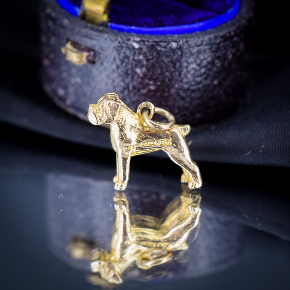 A solid 9ct yellow gold charm shaped as a standing boxer dog with visible hallmarks stamped on its side. View VI