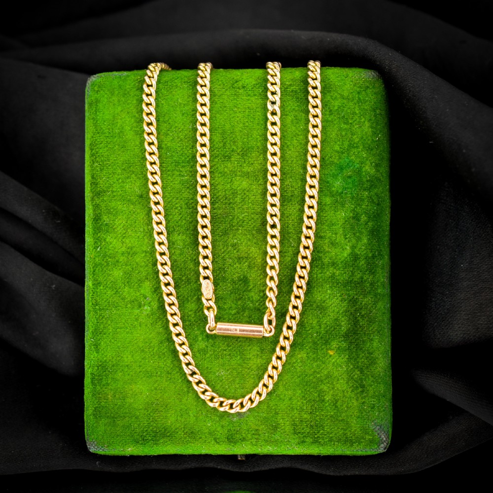 An antique 9ct yellow gold flat curb link chain necklace featuring a cylindrical barrel clasp.