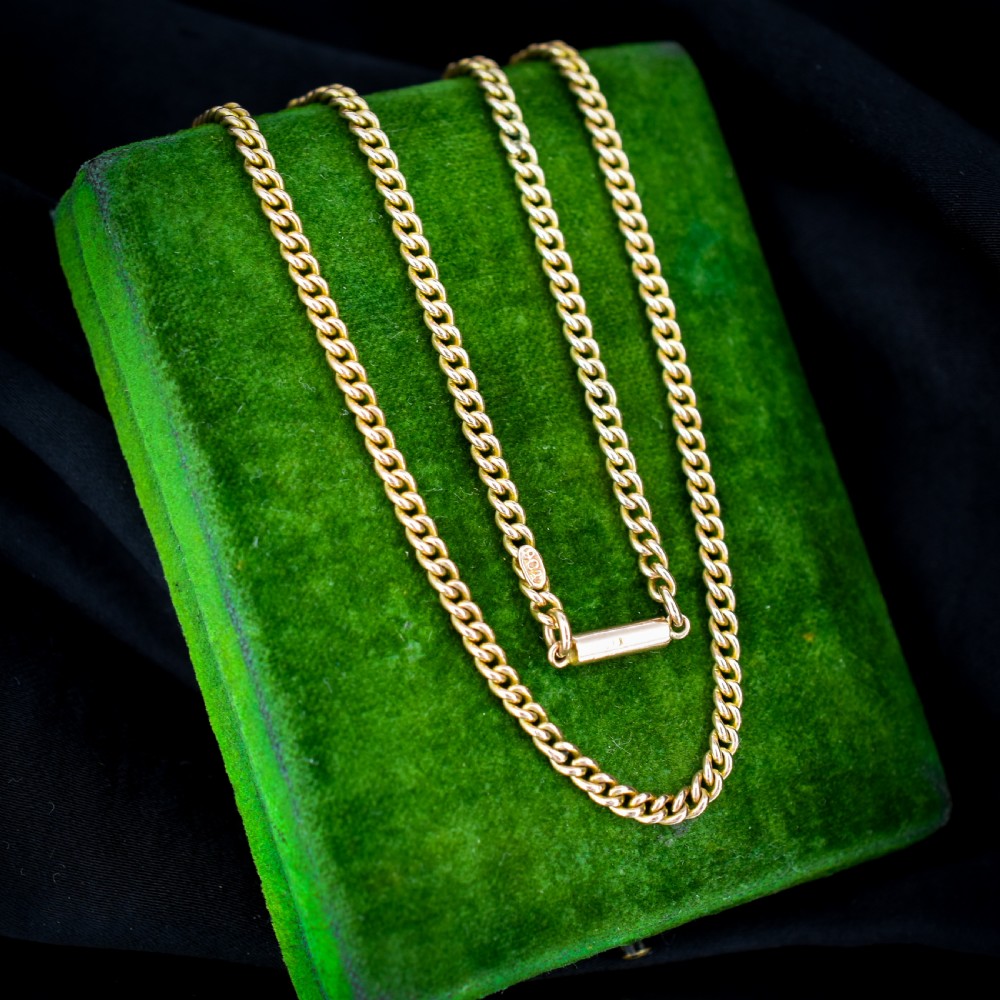 An antique 9ct yellow gold flat curb link chain necklace featuring a cylindrical barrel clasp. View V