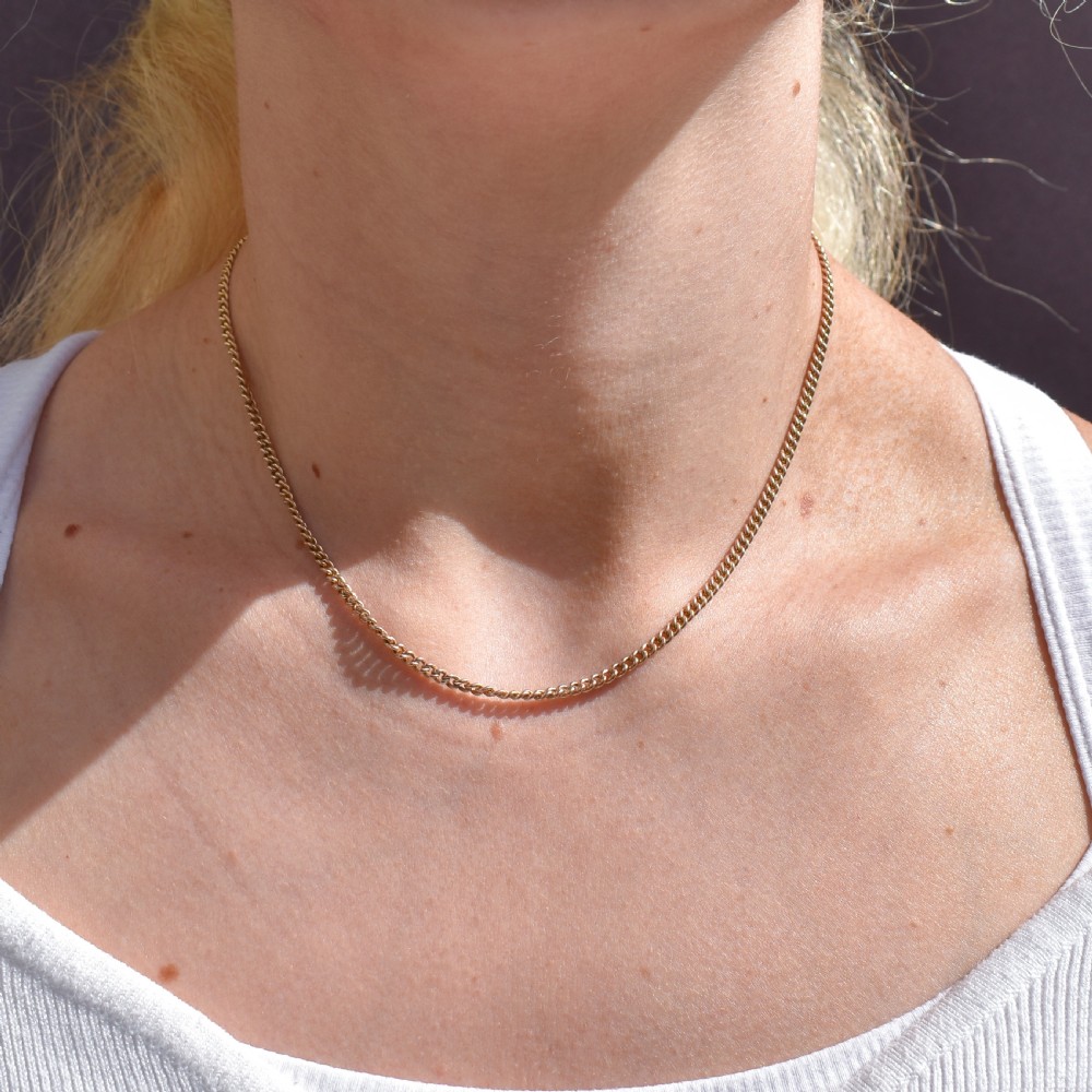 An antique 9ct yellow gold flat curb link chain necklace featuring a cylindrical barrel clasp. View XI