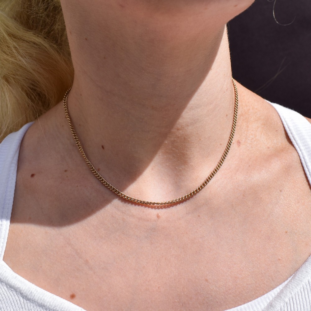 An antique 9ct yellow gold flat curb link chain necklace featuring a cylindrical barrel clasp. View XII