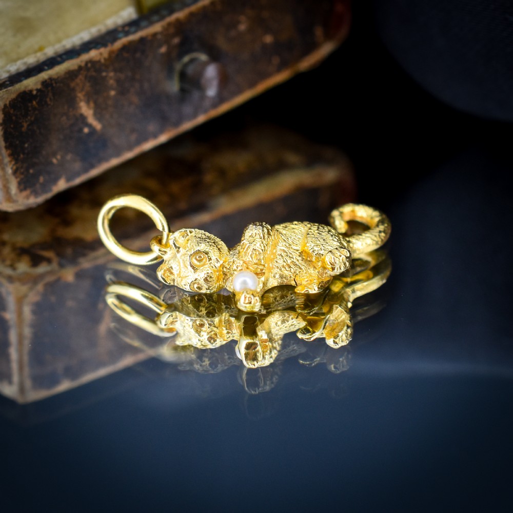 A 9ct yellow gold cat charm in a seated pose with textured fur detail holding a small cultured pearl in its paws. View II