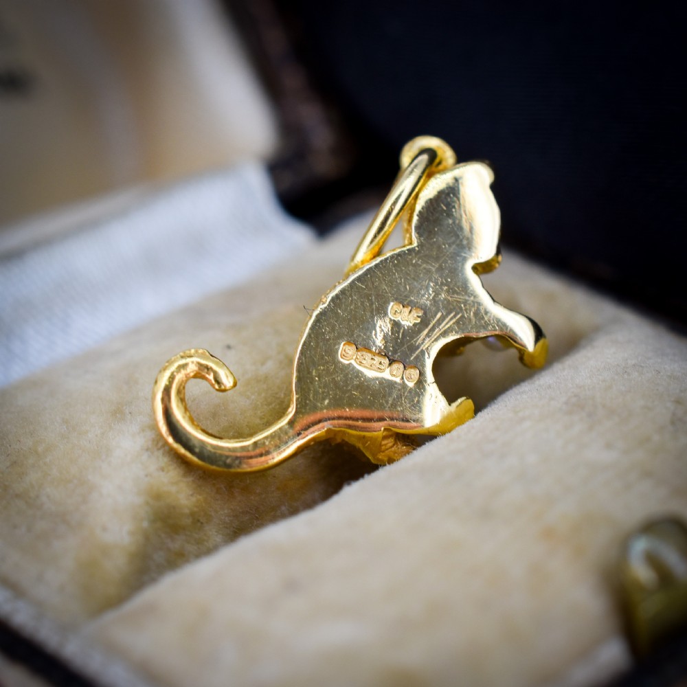A 9ct yellow gold cat charm in a seated pose with textured fur detail holding a small cultured pearl in its paws. View IV
