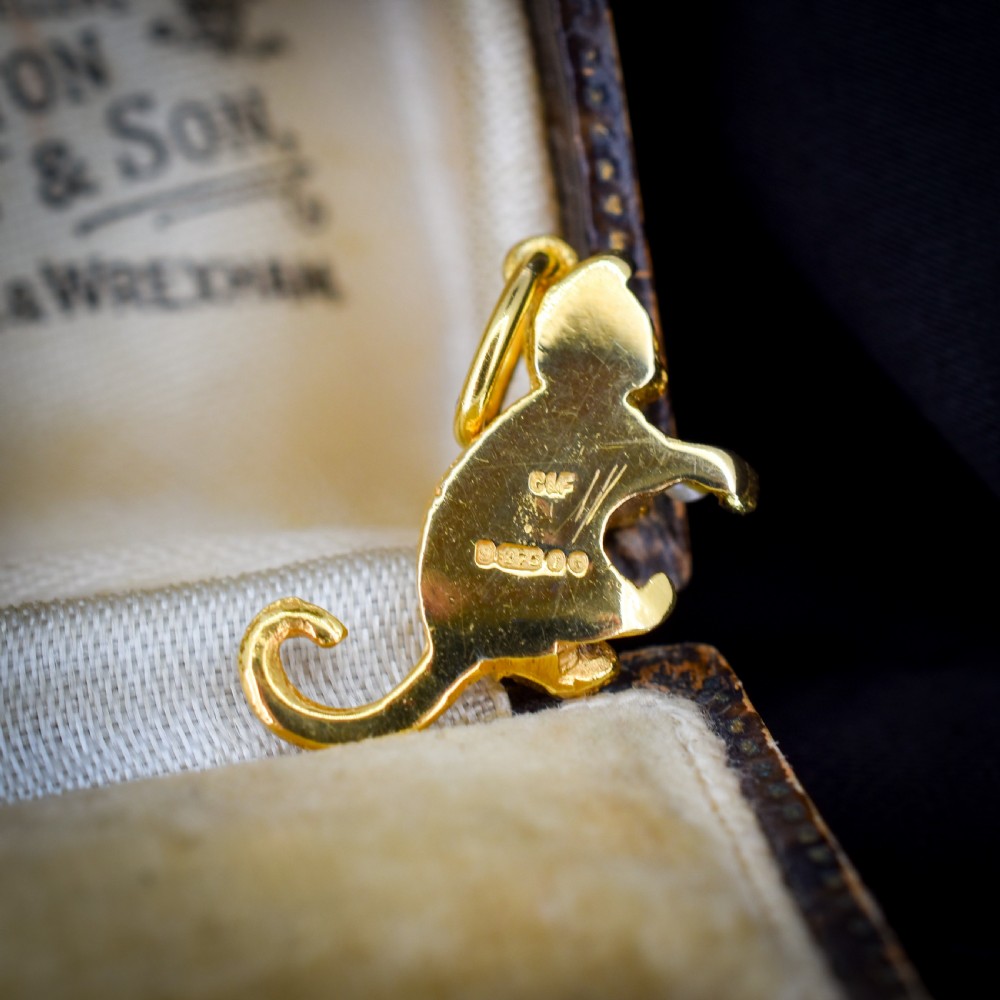 A 9ct yellow gold cat charm in a seated pose with textured fur detail holding a small cultured pearl in its paws. View VII