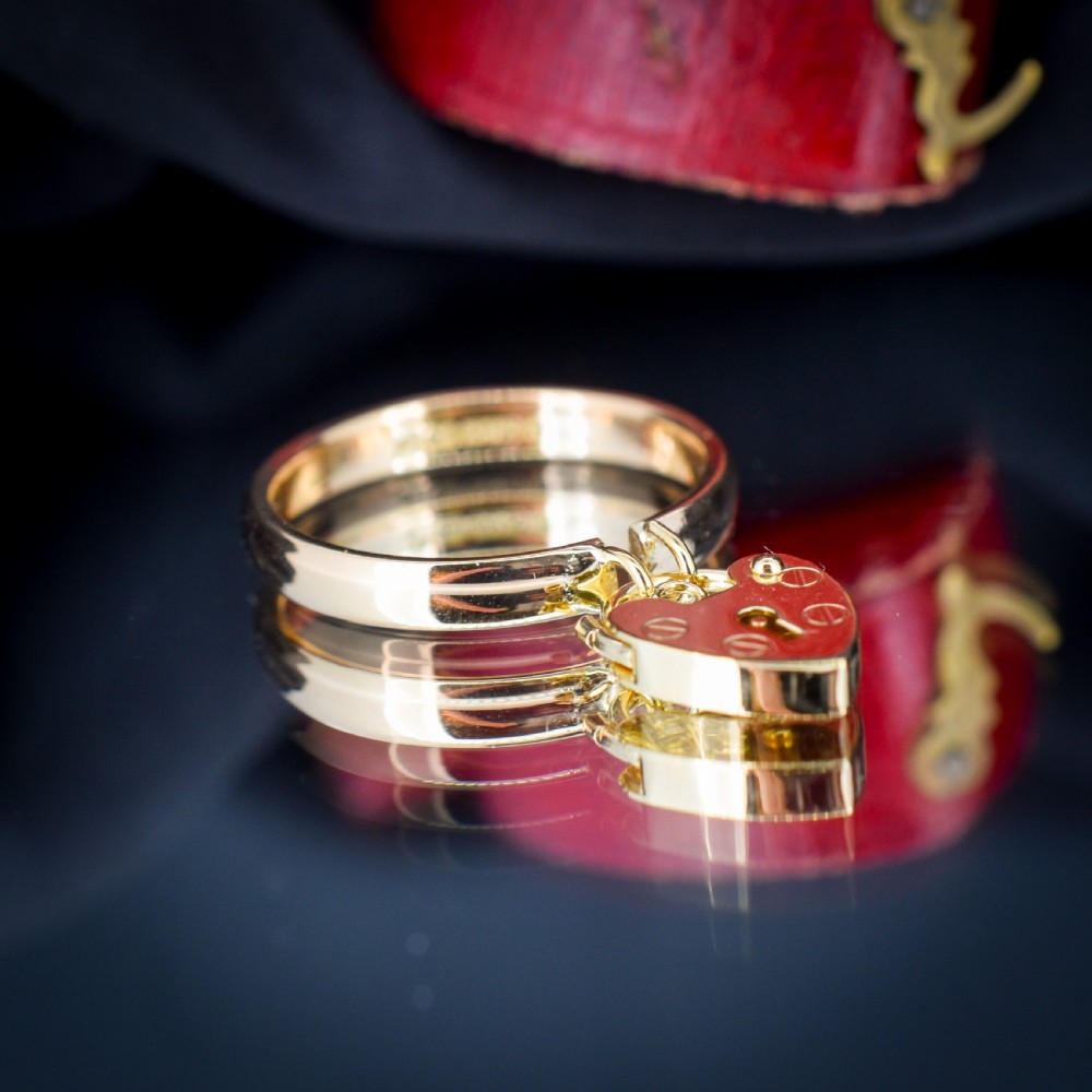 A 9ct yellow gold band ring featuring a dangling heart-shaped padlock charm suspended from two central loops. View III
