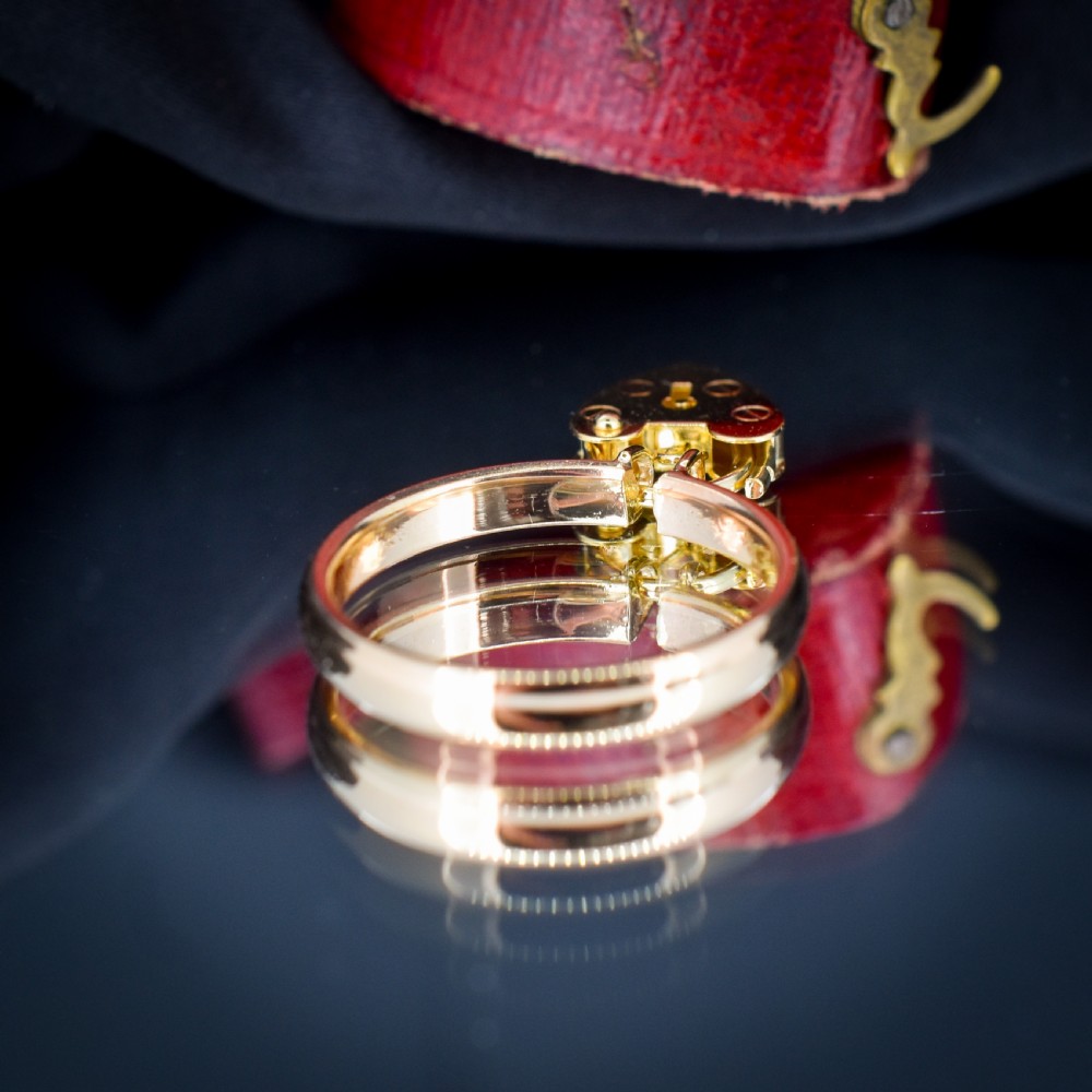 A 9ct yellow gold band ring featuring a dangling heart-shaped padlock charm suspended from two central loops. View IV