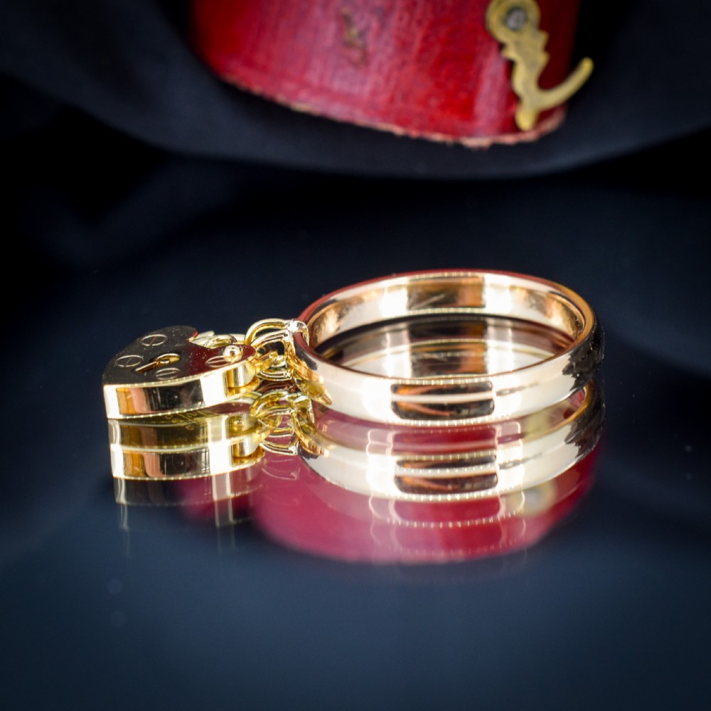 A 9ct yellow gold band ring featuring a dangling heart-shaped padlock charm suspended from two central loops. View V