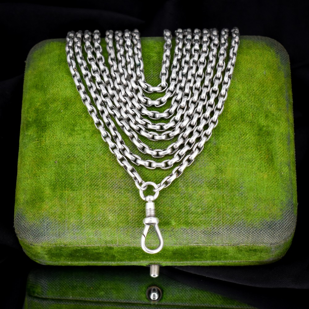 An antique silver long guard chain featuring multiple loops of belcher links terminating in a swivel dog clip clasp.