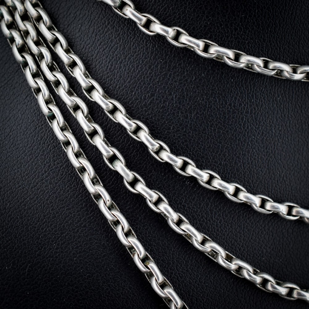 An antique silver long guard chain featuring multiple loops of belcher links terminating in a swivel dog clip clasp. View V