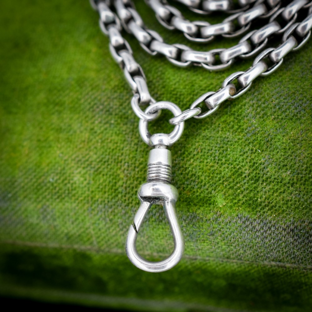 An antique silver long guard chain featuring multiple loops of belcher links terminating in a swivel dog clip clasp. View VIII