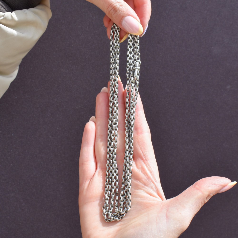 An antique silver long guard chain featuring multiple loops of belcher links terminating in a swivel dog clip clasp. View IX