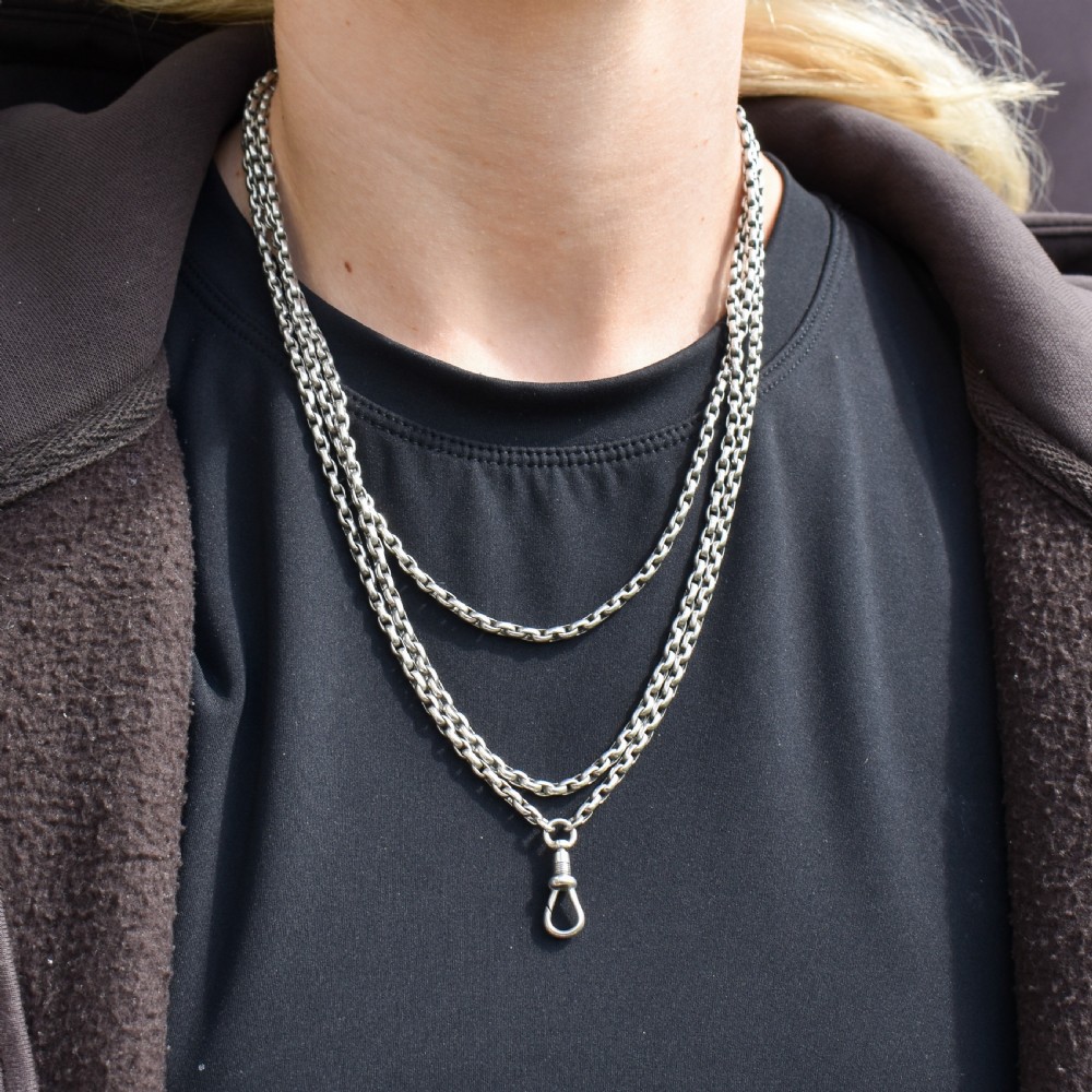 An antique silver long guard chain featuring multiple loops of belcher links terminating in a swivel dog clip clasp. View XI