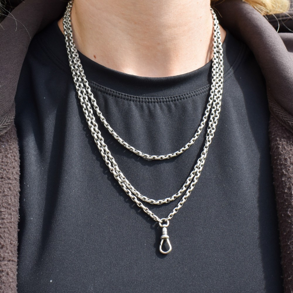 An antique silver long guard chain featuring multiple loops of belcher links terminating in a swivel dog clip clasp. View XII