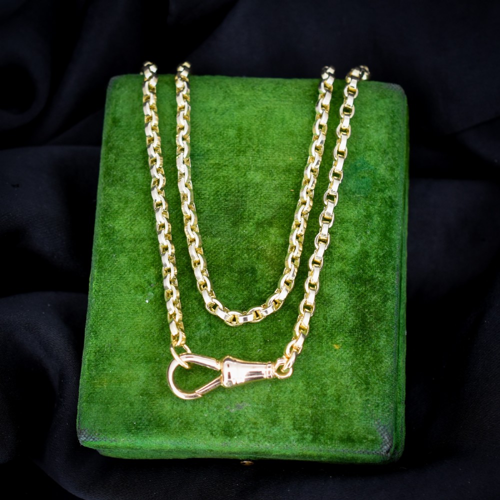 An antique 9ct yellow gold chain necklace featuring uniform oval links and a dog clip clasp displayed on a green velvet surface.