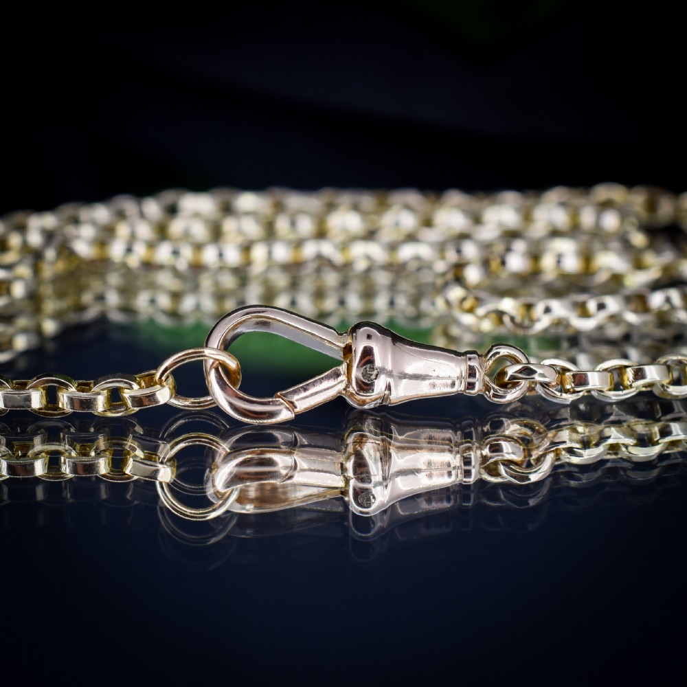 An antique 9ct yellow gold chain necklace featuring uniform oval links and a dog clip clasp displayed on a green velvet surface. View III