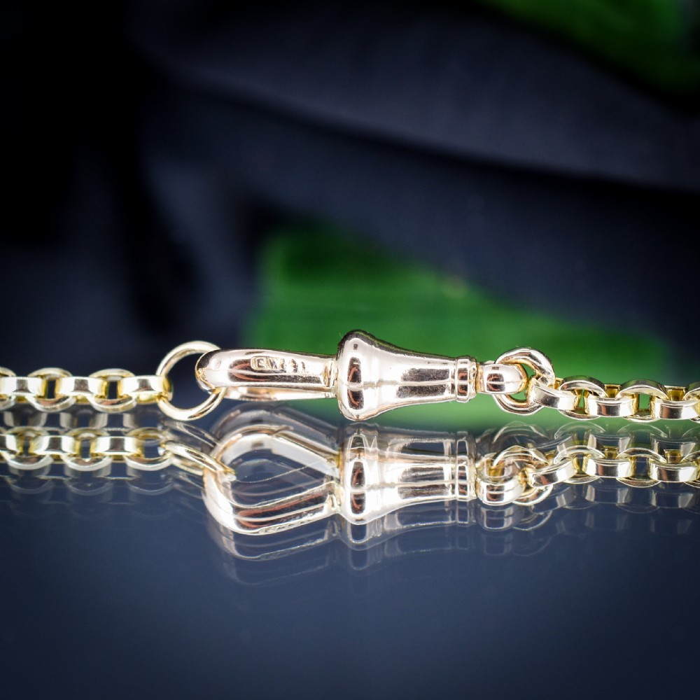 An antique 9ct yellow gold chain necklace featuring uniform oval links and a dog clip clasp displayed on a green velvet surface. View IV
