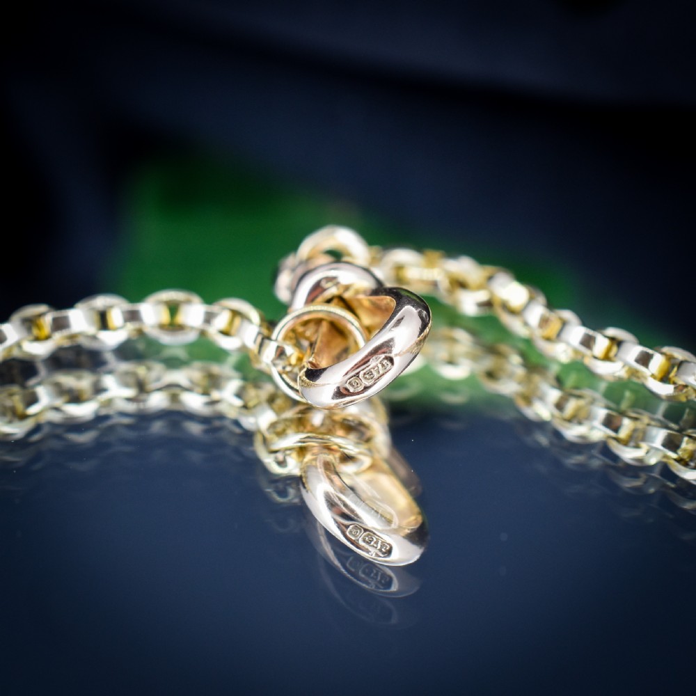 An antique 9ct yellow gold chain necklace featuring uniform oval links and a dog clip clasp displayed on a green velvet surface. View VI