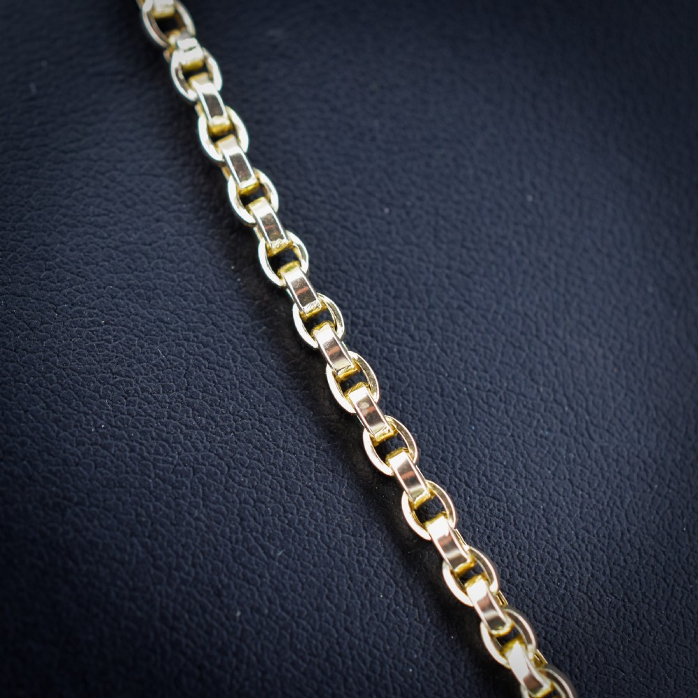 An antique 9ct yellow gold chain necklace featuring uniform oval links and a dog clip clasp displayed on a green velvet surface. View VII