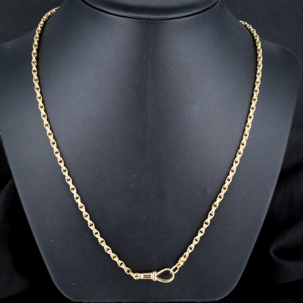 An antique 9ct yellow gold fancy link chain necklace with a dog clip clasp displayed on a green surface. View II