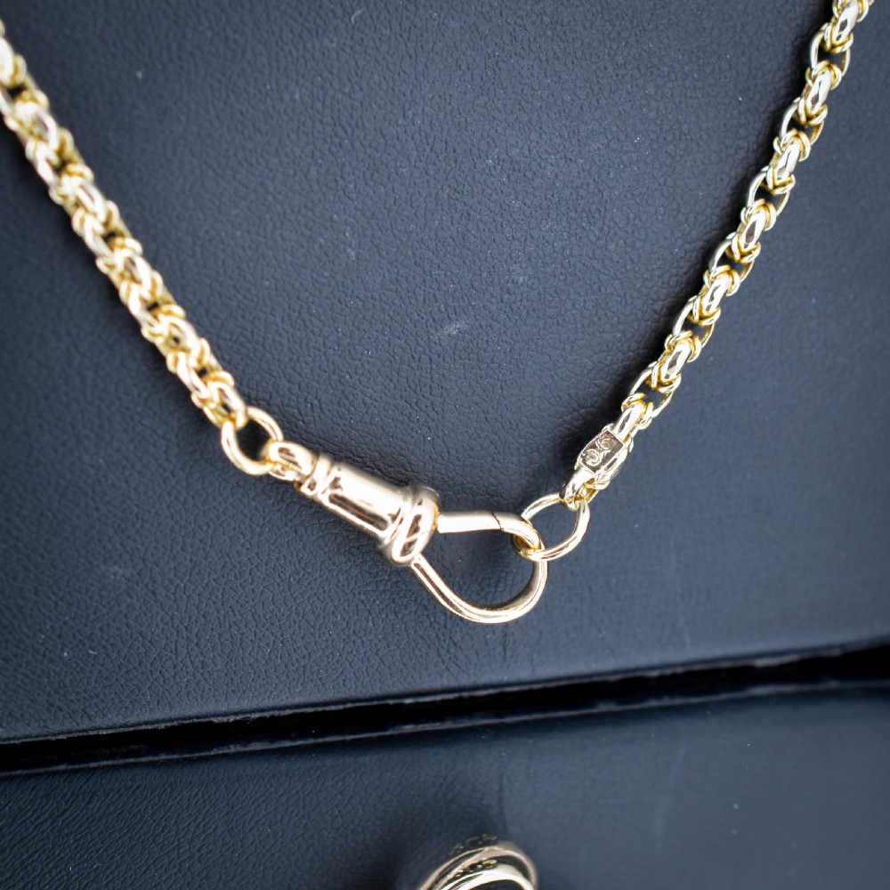 An antique 9ct yellow gold fancy link chain necklace with a dog clip clasp displayed on a green surface. View III