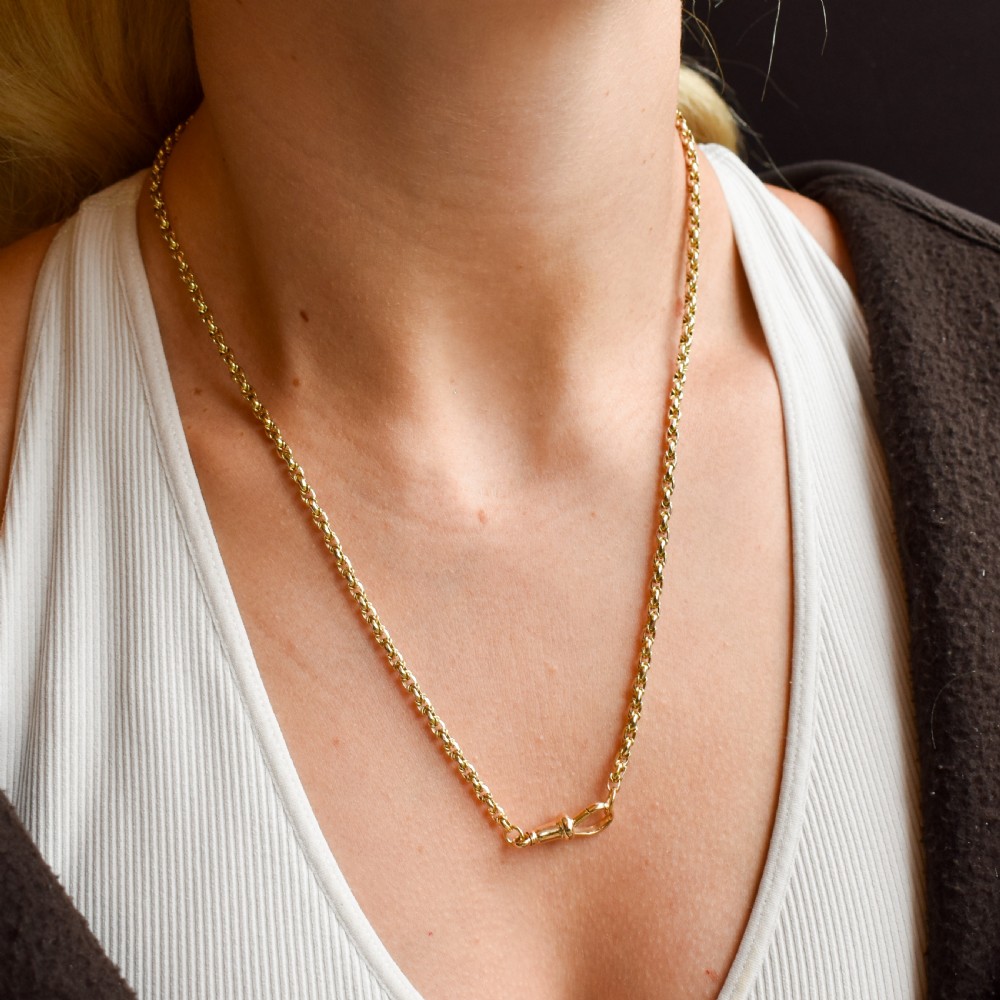 An antique 9ct yellow gold fancy link chain necklace with a dog clip clasp displayed on a green surface. View VIII
