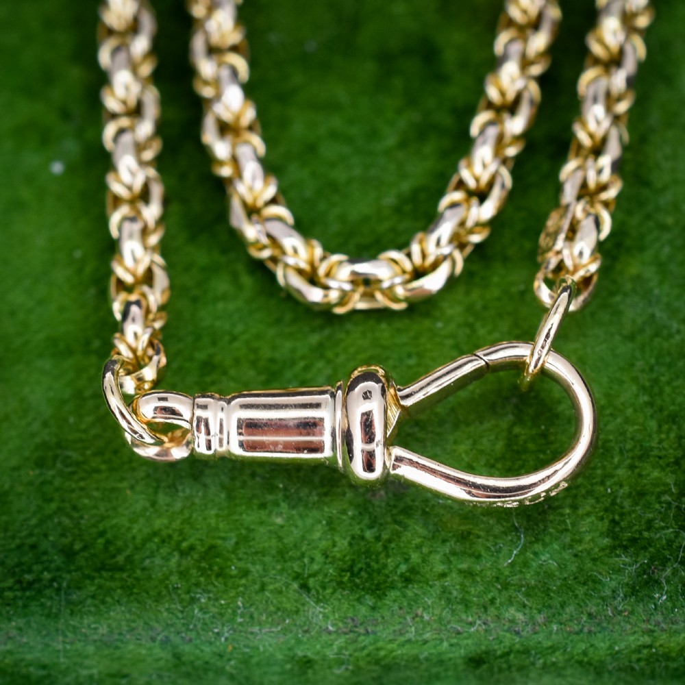 An antique 9ct yellow gold fancy link chain necklace with a dog clip clasp displayed on a green surface. View IX