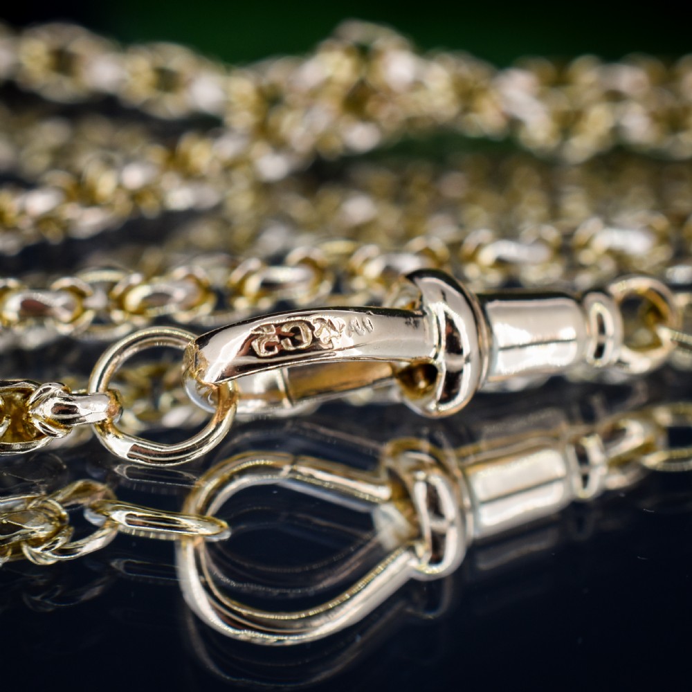 An antique 9ct yellow gold fancy link chain necklace with a dog clip clasp displayed on a green surface. View XII