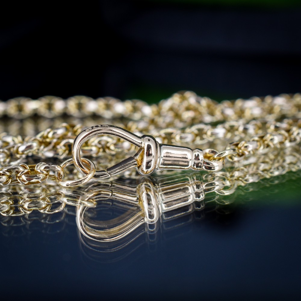 An antique 9ct yellow gold fancy link chain necklace with a dog clip clasp displayed on a green surface. View XIII
