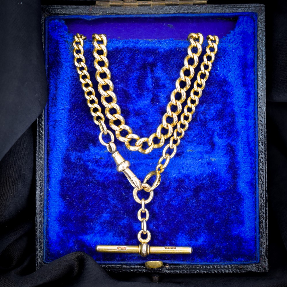 An antique 15ct yellow gold curb link Albert watch chain featuring a T-bar, dog clip, and bolt ring fastener, displayed inside a velvet fitted box.
