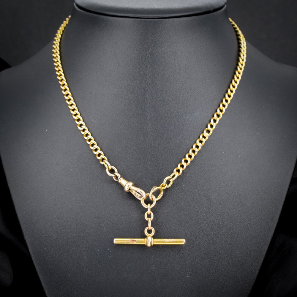 An antique 15ct yellow gold curb link Albert watch chain featuring a T-bar, dog clip, and bolt ring fastener, displayed inside a velvet fitted box. View II