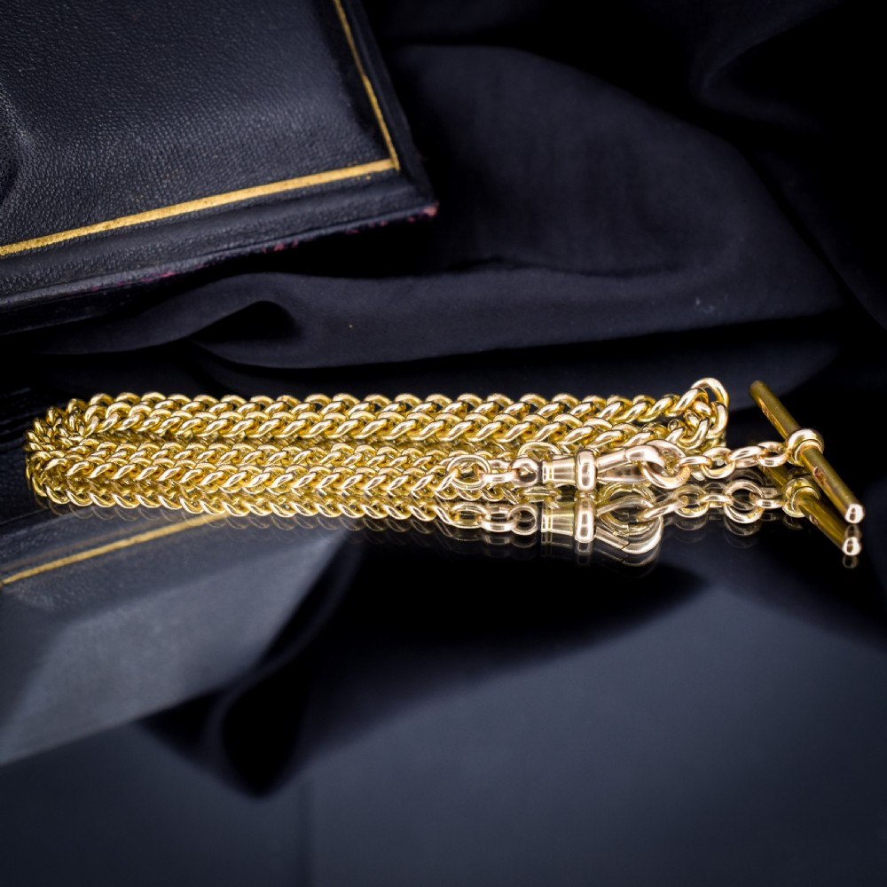 An antique 15ct yellow gold curb link Albert watch chain featuring a T-bar, dog clip, and bolt ring fastener, displayed inside a velvet fitted box. View V