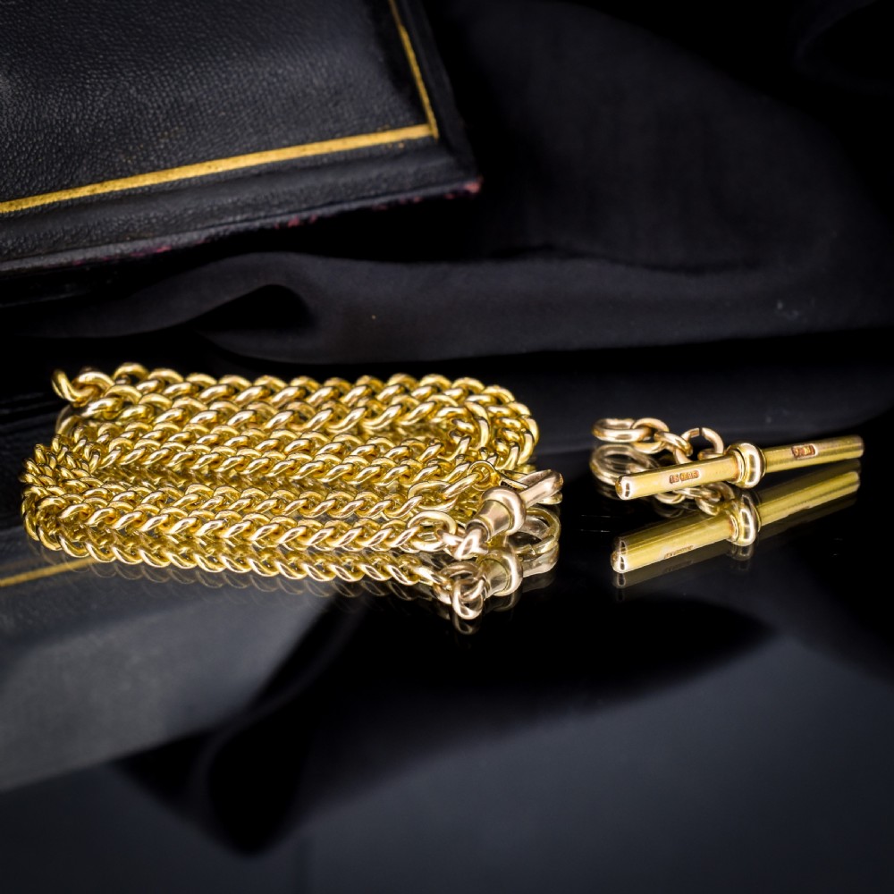 An antique 15ct yellow gold curb link Albert watch chain featuring a T-bar, dog clip, and bolt ring fastener, displayed inside a velvet fitted box. View VI