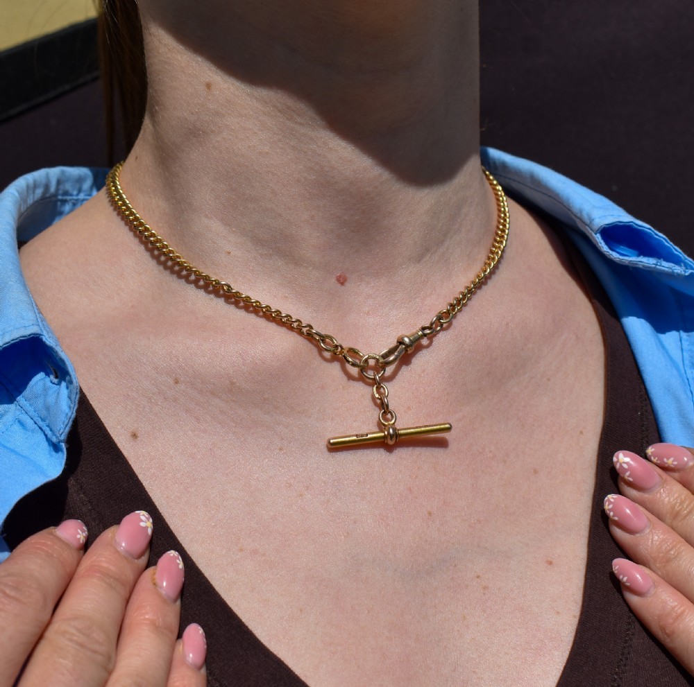 An antique 15ct yellow gold curb link Albert watch chain featuring a T-bar, dog clip, and bolt ring fastener, displayed inside a velvet fitted box. View XV