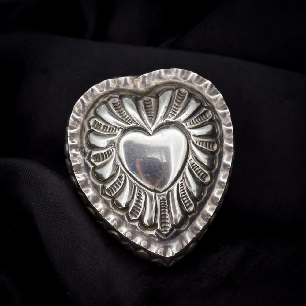 An open heart-shaped sterling silver ring box featuring an embossed gilt interior lid and a green velvet base slot for a ring. View II
