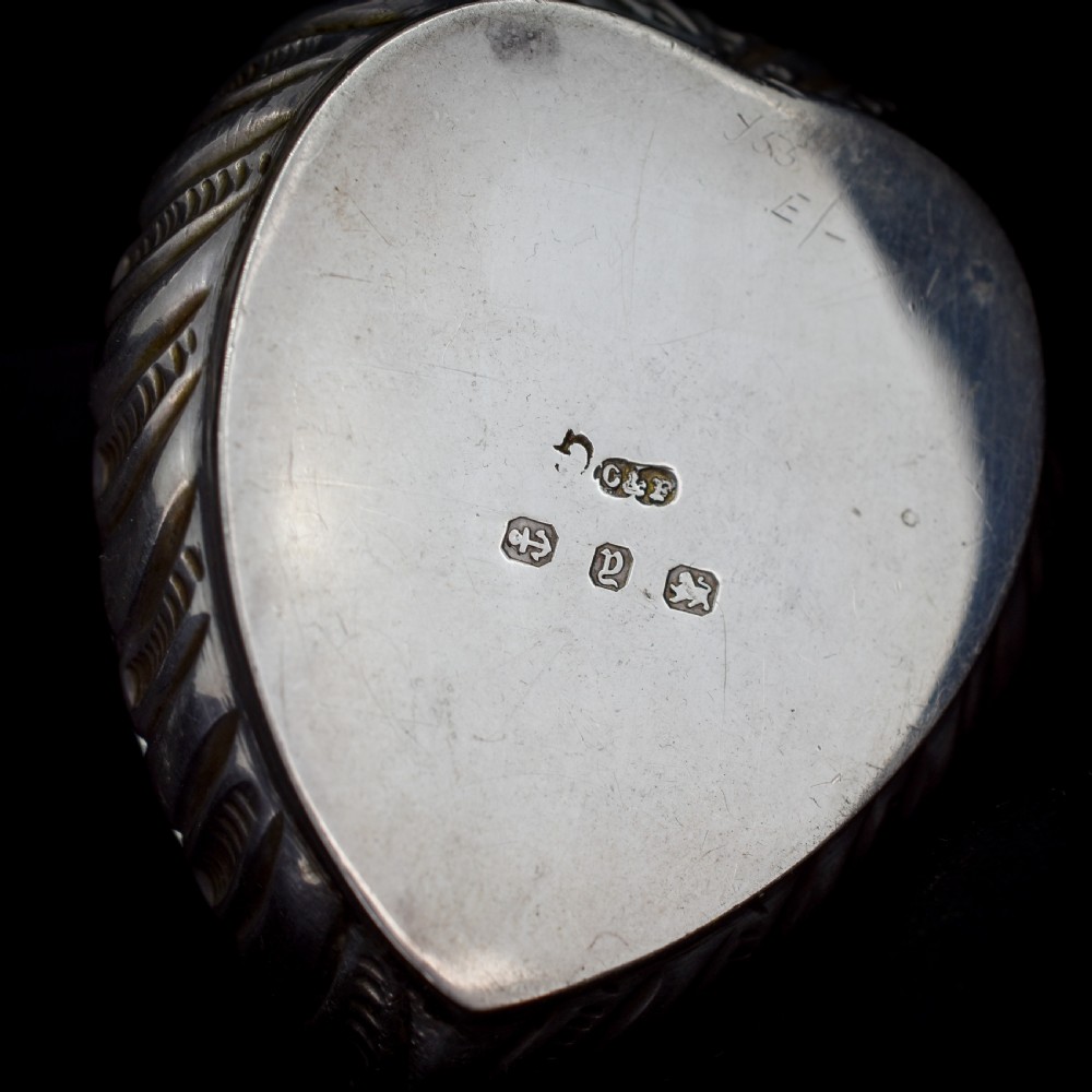 An open heart-shaped sterling silver ring box featuring an embossed gilt interior lid and a green velvet base slot for a ring. View III