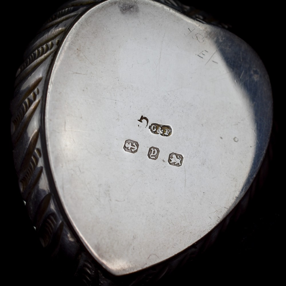 An open heart-shaped sterling silver ring box featuring an embossed gilt interior lid and a green velvet base slot for a ring. View IV
