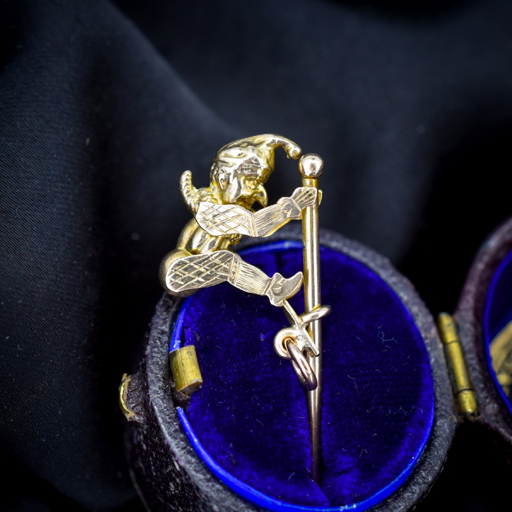 An antique 9ct yellow gold charm depicting the character Mr Punch sliding down a central vertical pin.