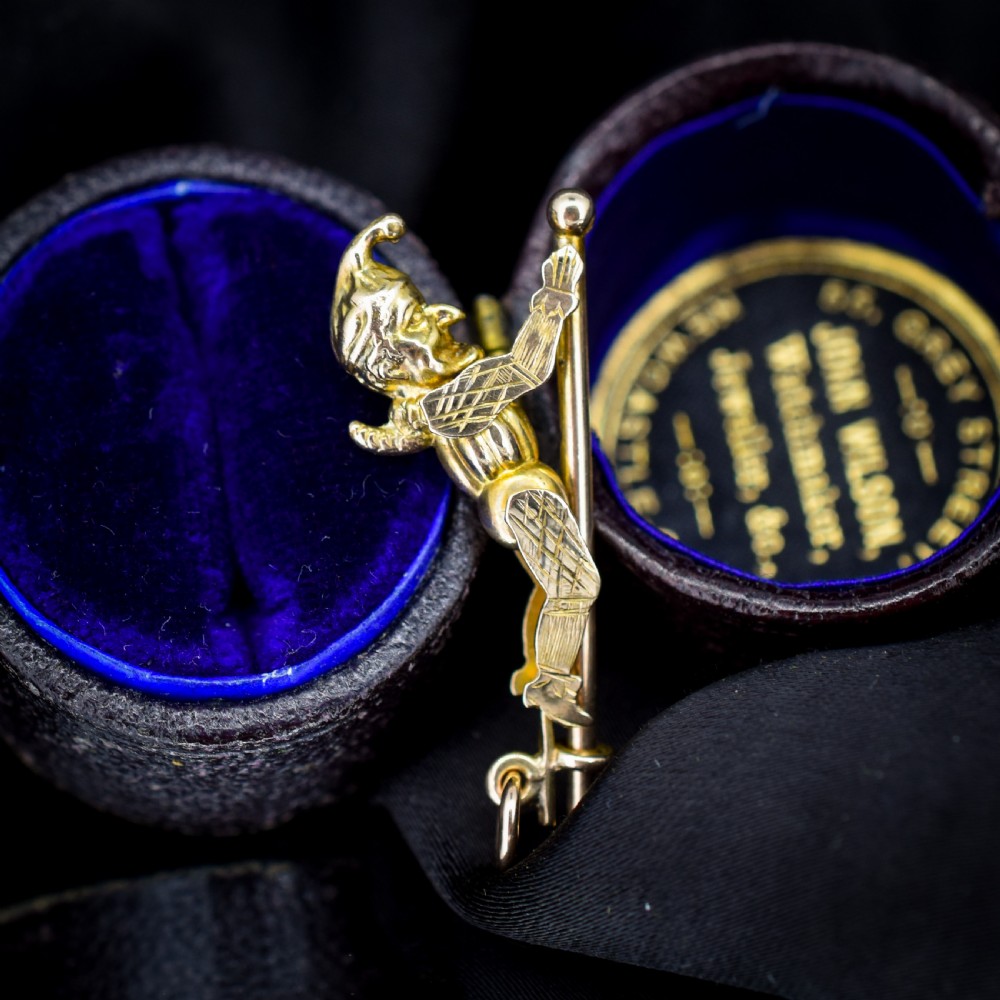 An antique 9ct yellow gold charm depicting the character Mr Punch sliding down a central vertical pin. View II