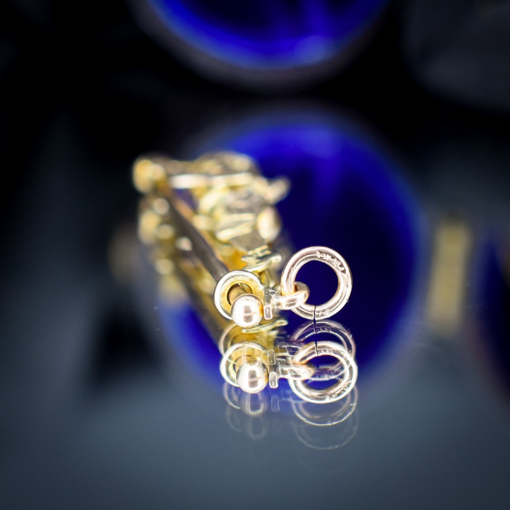 An antique 9ct yellow gold charm depicting the character Mr Punch sliding down a central vertical pin. View V
