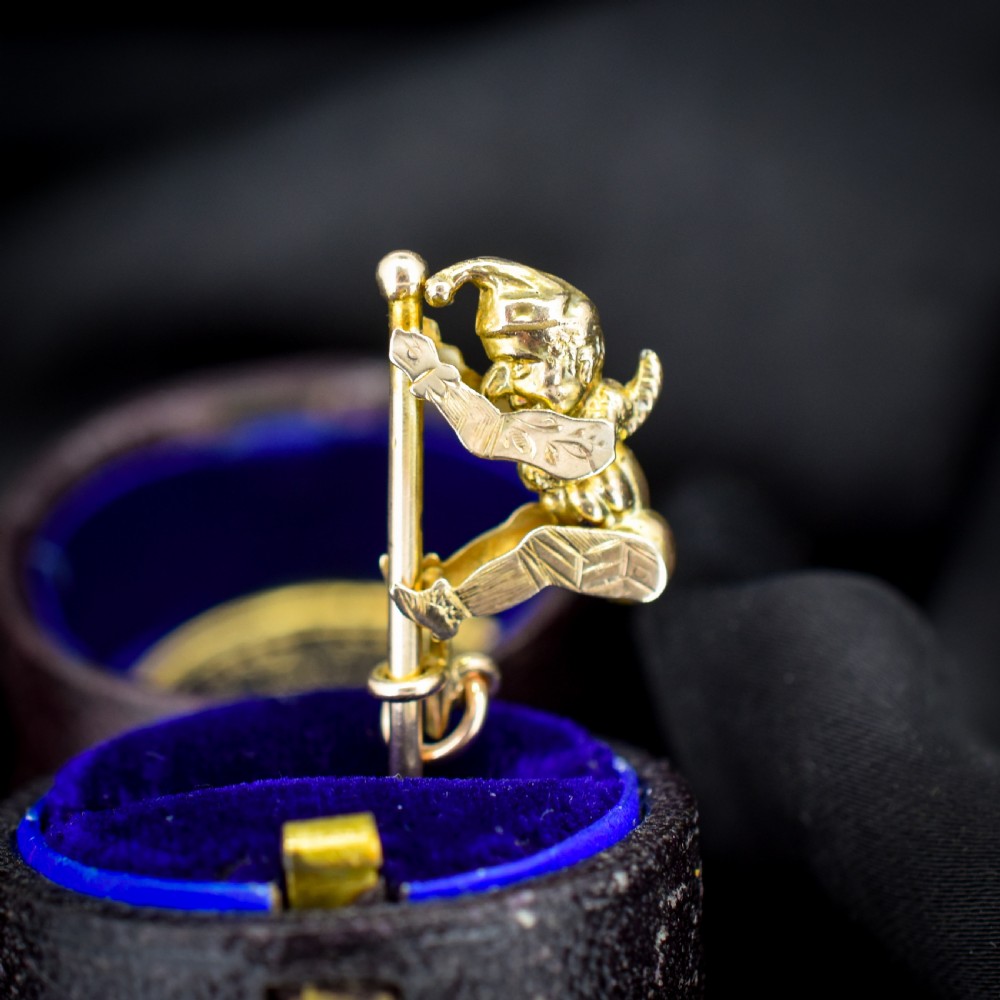 An antique 9ct yellow gold charm depicting the character Mr Punch sliding down a central vertical pin. View VI