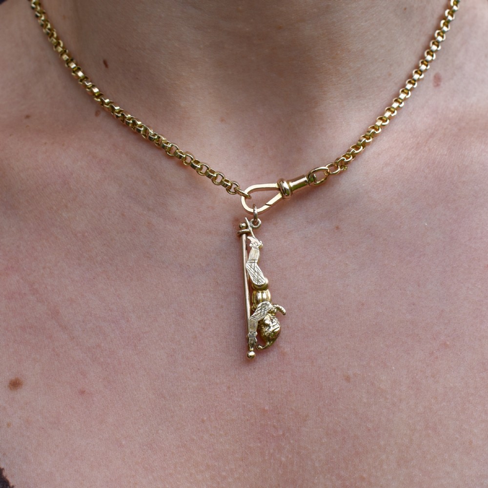 An antique 9ct yellow gold charm depicting the character Mr Punch sliding down a central vertical pin. View VIII