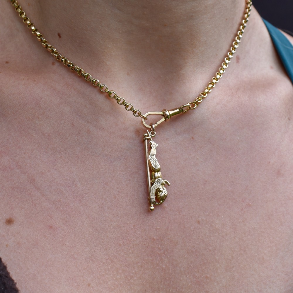 An antique 9ct yellow gold charm depicting the character Mr Punch sliding down a central vertical pin. View IX