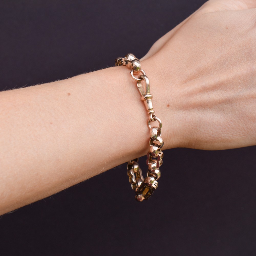 An antique 9ct gold chain bracelet featuring alternating star-and-bar decorative links and faceted round links with a swivel clasp. View X